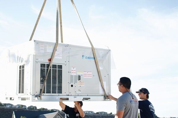 Five Star team using a crane to set a new Daikin rooftop package unit during a commercial installation in St. George, Utah