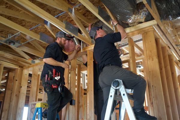 Two Five Star techs running flex duct in a new construction home