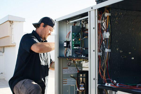 Five Star technician kneeling at a rooftop HVAC package unit during a service call in St. George, Utah