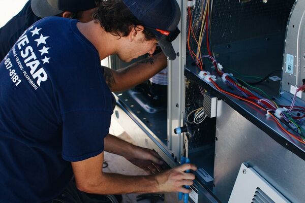 Two Five Star technicians servicing a commercial rooftop HVAC package unit in St. George, Utah